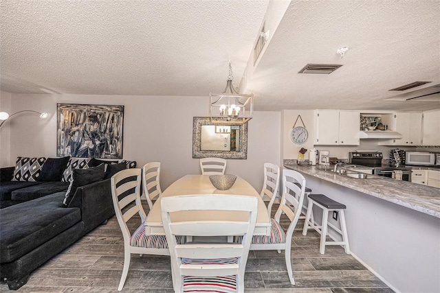 dining area with wood finish floors, visible vents, and a textured ceiling