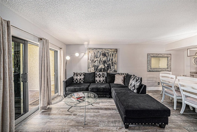 living room featuring wood finished floors, baseboards, and a textured ceiling