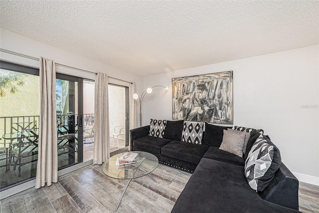 living area featuring a textured ceiling, baseboards, and wood finished floors