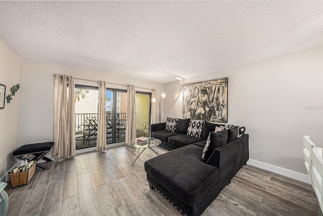 living area featuring a textured ceiling, baseboards, and wood finished floors