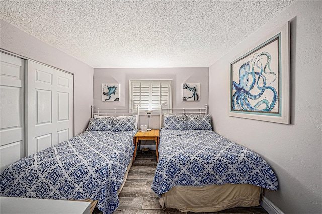 bedroom featuring baseboards, wood finished floors, a textured wall, a closet, and a textured ceiling