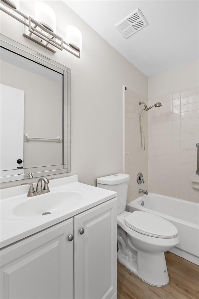 bathroom featuring shower / bathtub combination, toilet, wood finished floors, vanity, and visible vents