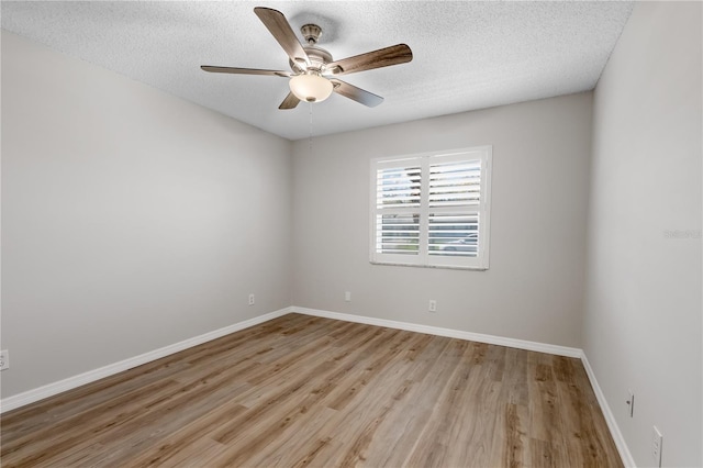 spare room featuring a ceiling fan, baseboards, light wood-style flooring, and a textured ceiling