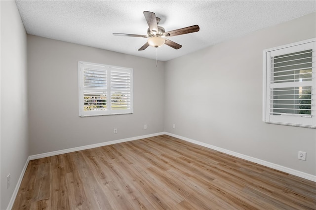 empty room with a textured ceiling, baseboards, a ceiling fan, and light wood-style floors