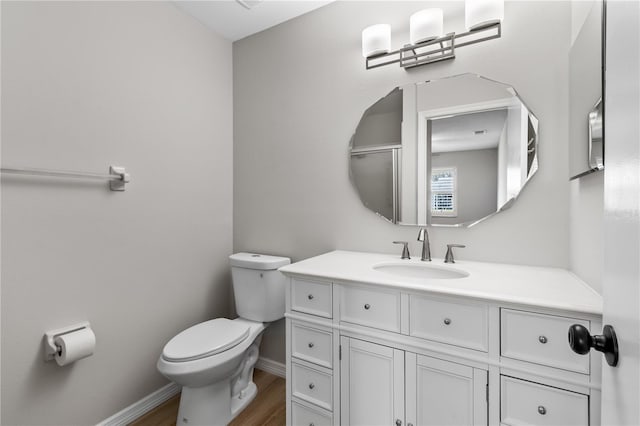 bathroom with toilet, baseboards, wood finished floors, and vanity