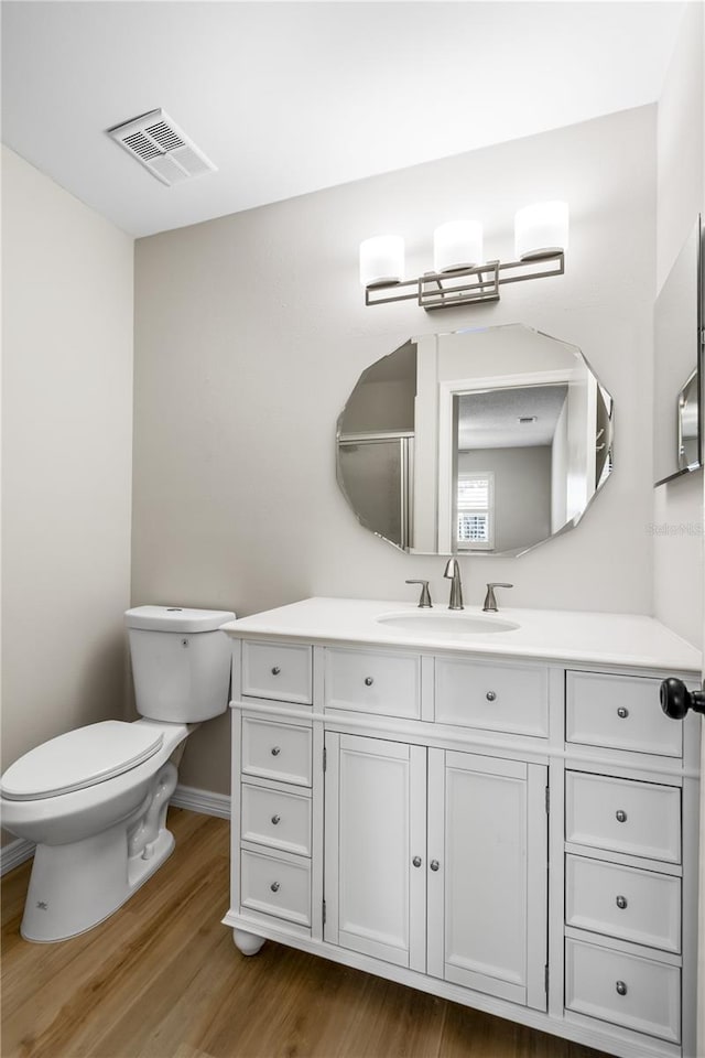 bathroom featuring visible vents, vanity, toilet, and wood finished floors