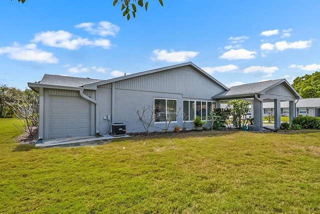 rear view of house with a yard, an attached garage, and central AC unit