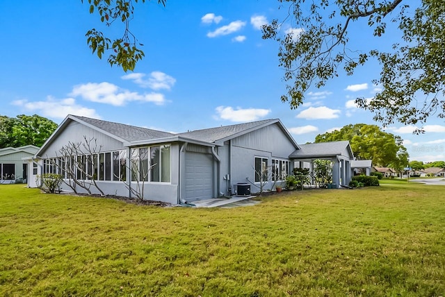 back of property featuring a yard, an attached garage, a sunroom, and central air condition unit