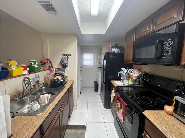 kitchen featuring light countertops, a sink, visible vents, and black appliances