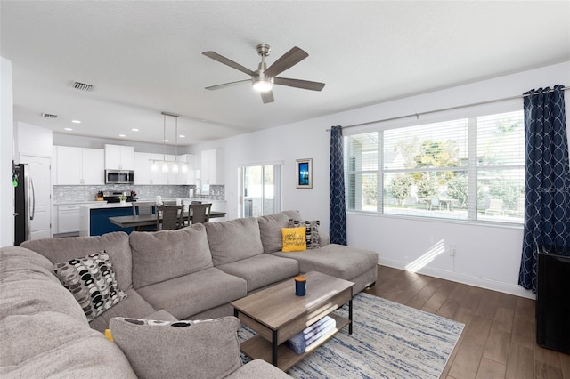 living area with a ceiling fan, dark wood finished floors, visible vents, and baseboards