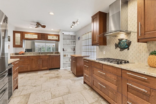 kitchen with decorative backsplash, ceiling fan, light stone counters, stainless steel appliances, and wall chimney range hood