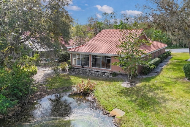 exterior space with driveway, a yard, a tiled roof, and stucco siding