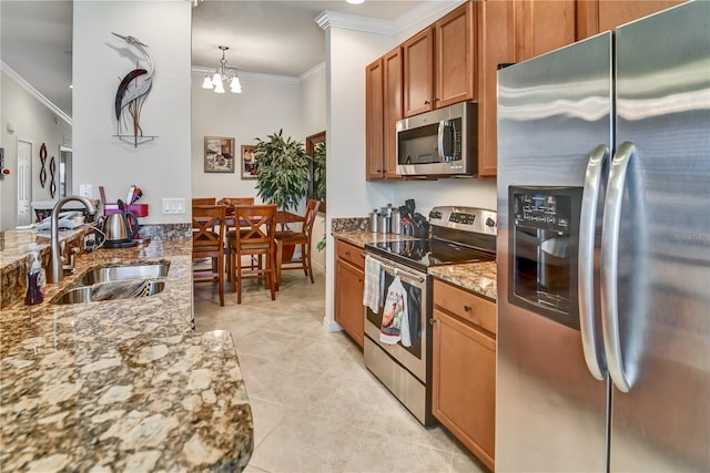 kitchen with a sink, ornamental molding, appliances with stainless steel finishes, light stone countertops, and brown cabinetry