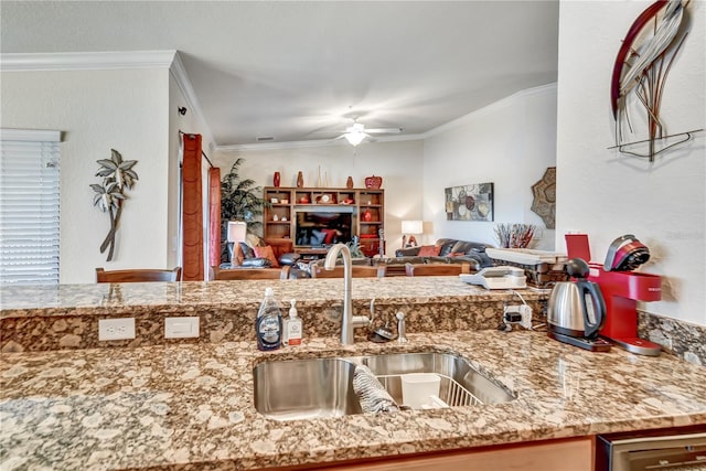 kitchen featuring crown molding, open floor plan, a sink, and ceiling fan