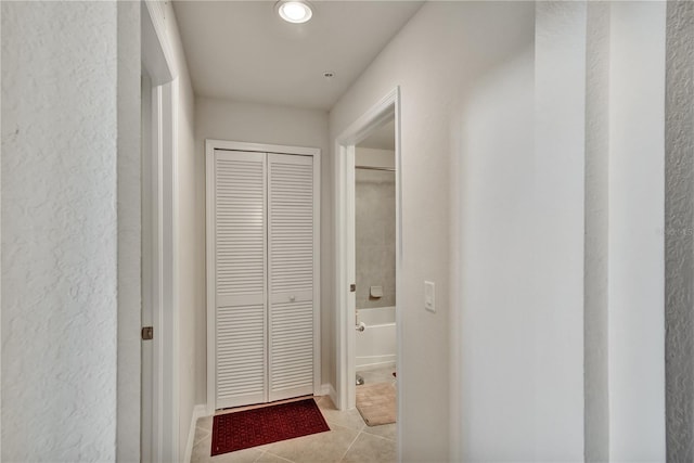 hallway featuring a textured wall and light tile patterned floors