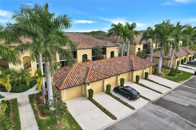 mediterranean / spanish-style home featuring a garage, driveway, a tile roof, and stucco siding