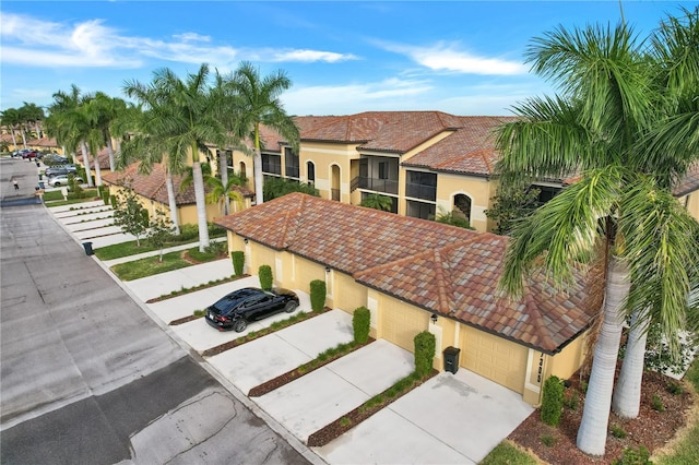 view of front of house featuring a garage, a tiled roof, driveway, and stucco siding