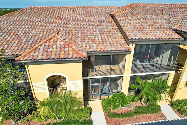 exterior space with a tile roof and stucco siding