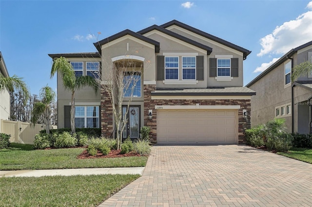 view of front of house featuring a garage, stone siding, fence, decorative driveway, and stucco siding