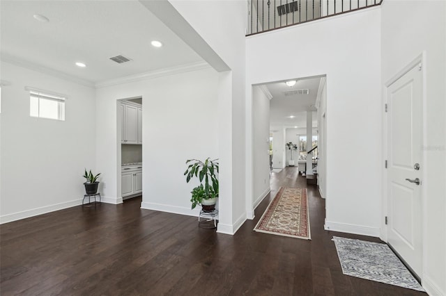 foyer featuring baseboards, visible vents, wood finished floors, and ornamental molding