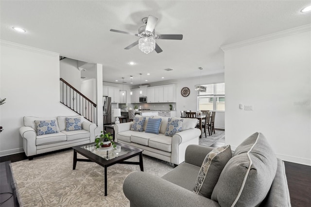 living area featuring crown molding, stairs, baseboards, and wood finished floors