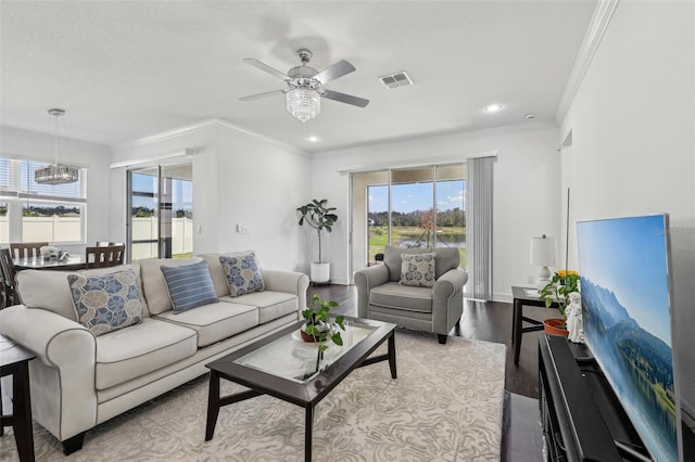 living area with baseboards, visible vents, wood finished floors, and ornamental molding