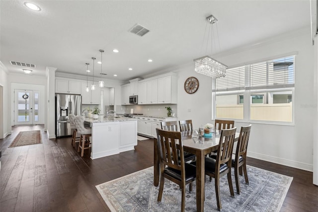 dining area with dark wood-style floors, visible vents, and crown molding