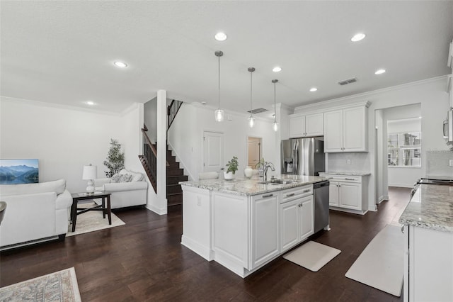 kitchen featuring stainless steel appliances, visible vents, open floor plan, white cabinetry, and a sink