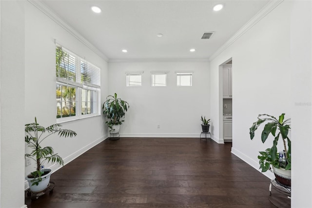 unfurnished room featuring baseboards, visible vents, dark wood-style flooring, and ornamental molding