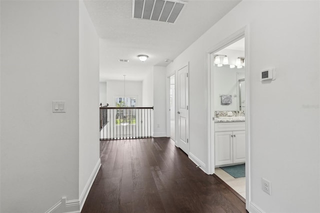 hallway featuring visible vents, baseboards, and wood finished floors