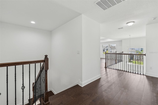 corridor featuring recessed lighting, wood finished floors, visible vents, an upstairs landing, and baseboards