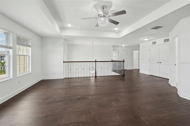 spare room with a tray ceiling, visible vents, and wood finished floors