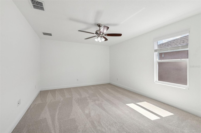 carpeted empty room with a ceiling fan, visible vents, and baseboards