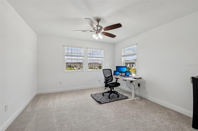 carpeted home office with a ceiling fan and baseboards