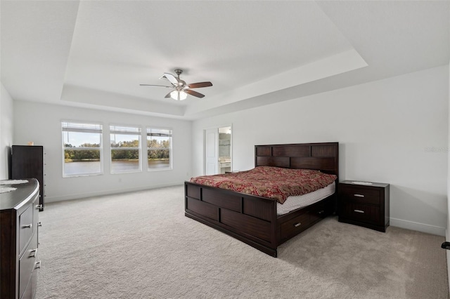 bedroom featuring light carpet, baseboards, and a tray ceiling