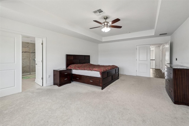 bedroom featuring light colored carpet, visible vents, and a tray ceiling