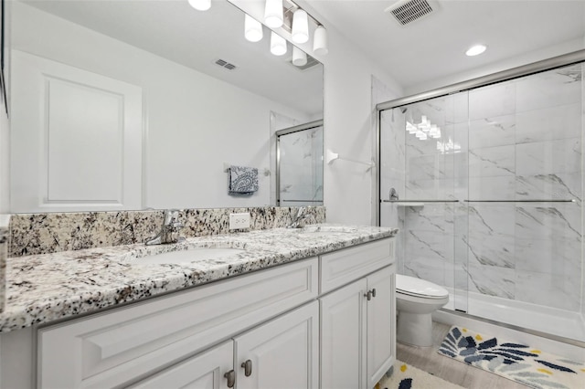 bathroom featuring a marble finish shower, a sink, and visible vents