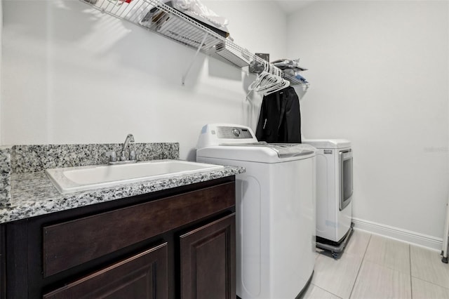 laundry room with cabinet space, light tile patterned flooring, a sink, washer and dryer, and baseboards