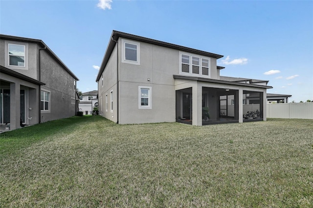 rear view of property featuring a sunroom, stucco siding, a yard, and fence