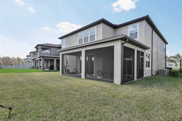 back of property featuring a yard, central AC, a sunroom, and stucco siding