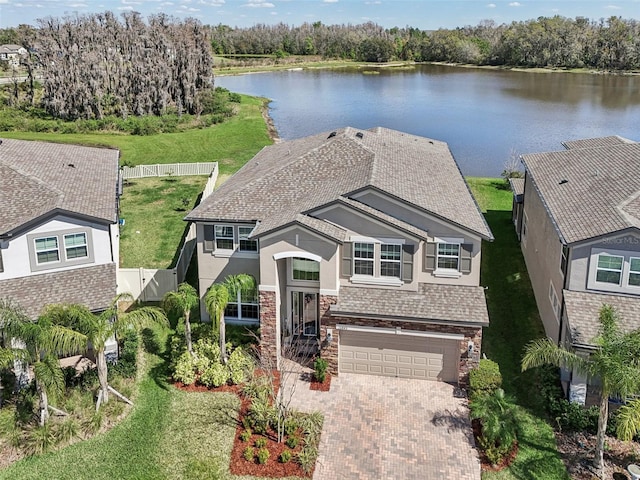 view of front of house featuring a water view, stone siding, decorative driveway, and stucco siding