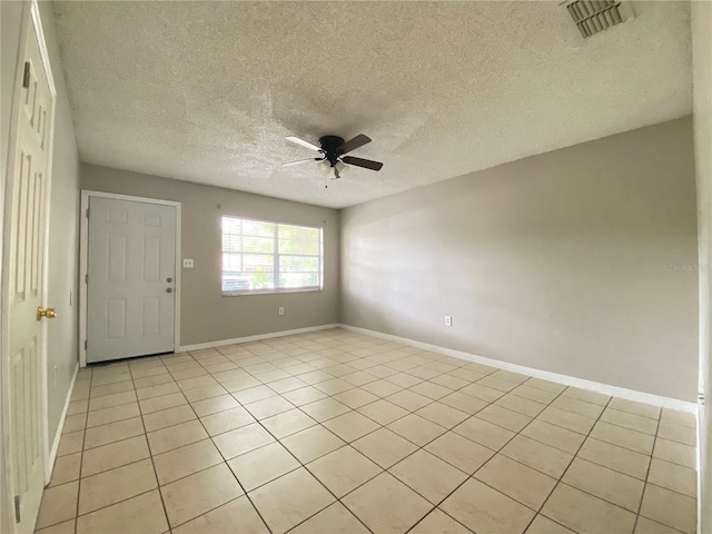 spare room featuring visible vents, a ceiling fan, a textured ceiling, light tile patterned flooring, and baseboards