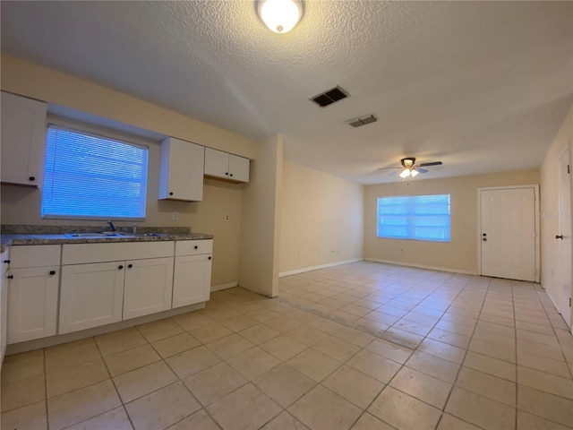 kitchen with a ceiling fan, visible vents, a sink, a textured ceiling, and white cabinetry