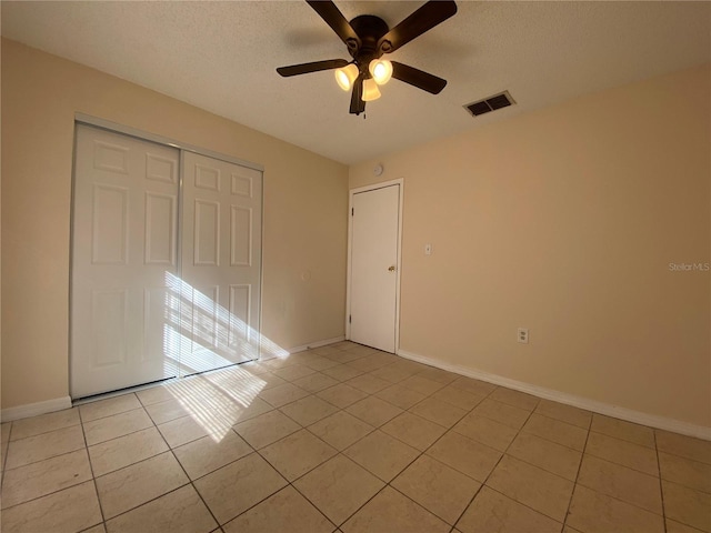 unfurnished bedroom with light tile patterned floors, baseboards, visible vents, and a closet