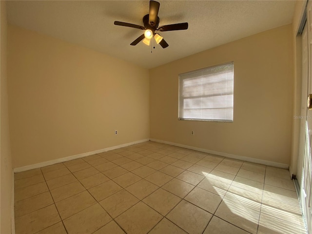 spare room with light tile patterned floors, ceiling fan, a textured ceiling, and baseboards