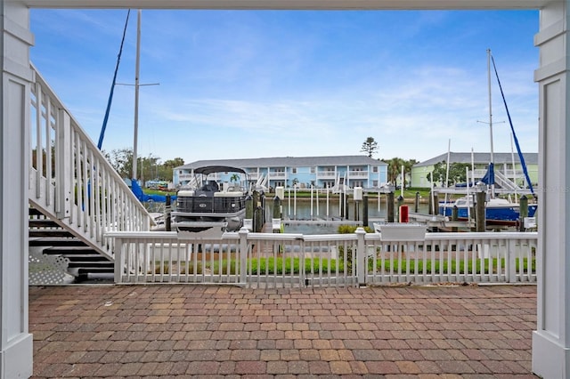 view of patio with a boat dock, boat lift, a residential view, a water view, and stairs