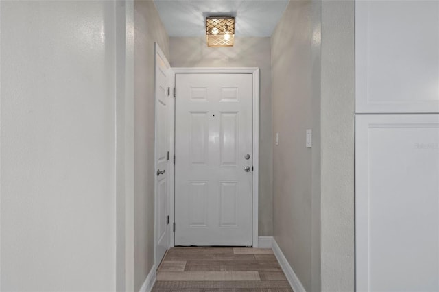 doorway to outside featuring baseboards and wood finished floors