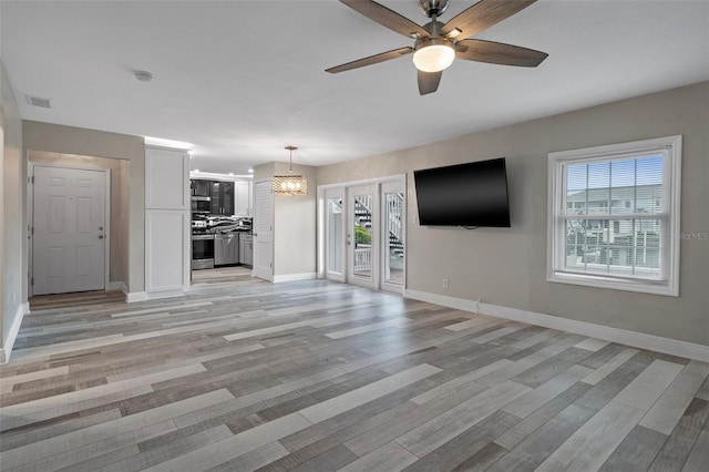 unfurnished living room featuring light wood finished floors, baseboards, and visible vents