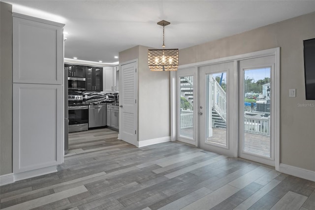 unfurnished dining area featuring light wood-type flooring, baseboards, a chandelier, and recessed lighting