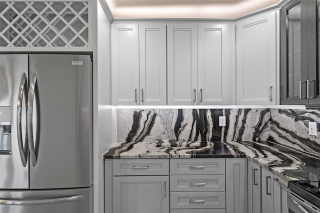 kitchen featuring stone countertops, white cabinets, stainless steel fridge with ice dispenser, tasteful backsplash, and glass insert cabinets